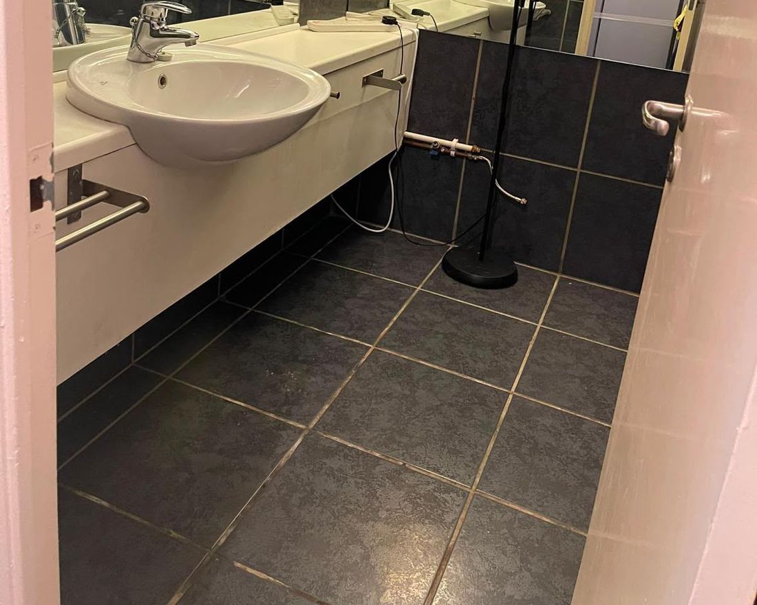 The same bathroom after cleaning: clear floor, clean basin and wiped-down tiles